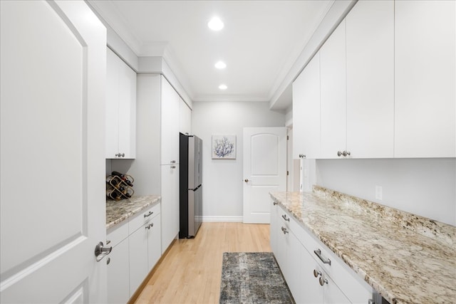 kitchen featuring ornamental molding, light stone countertops, white cabinets, and light hardwood / wood-style floors