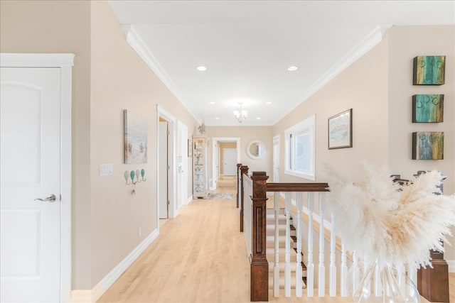 corridor featuring crown molding, light wood-type flooring, and a chandelier