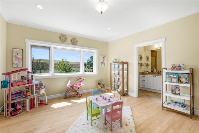 game room featuring light wood-type flooring and ornamental molding