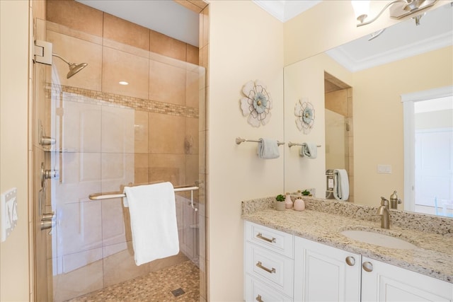 bathroom with a shower with shower door, vanity, and ornamental molding