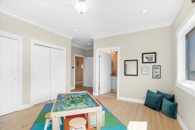 game room featuring ornamental molding and light hardwood / wood-style flooring