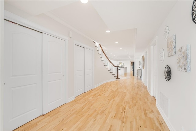 hall with light hardwood / wood-style floors and crown molding