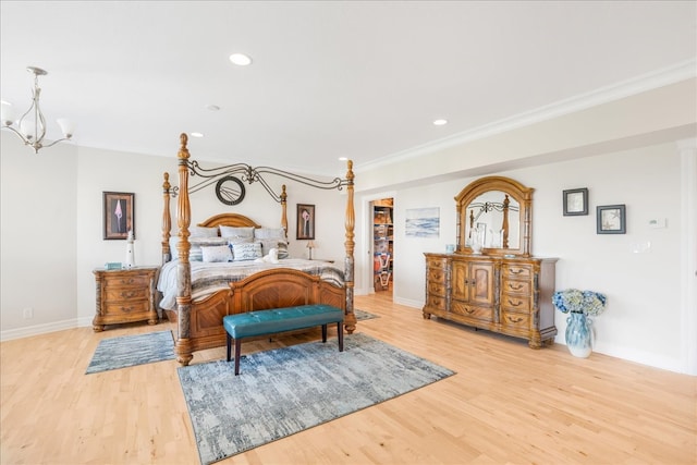 bedroom featuring ornamental molding, a walk in closet, a closet, and light wood-type flooring