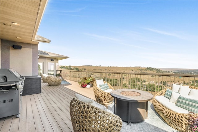 wooden terrace with an outdoor living space with a fire pit, a rural view, and area for grilling