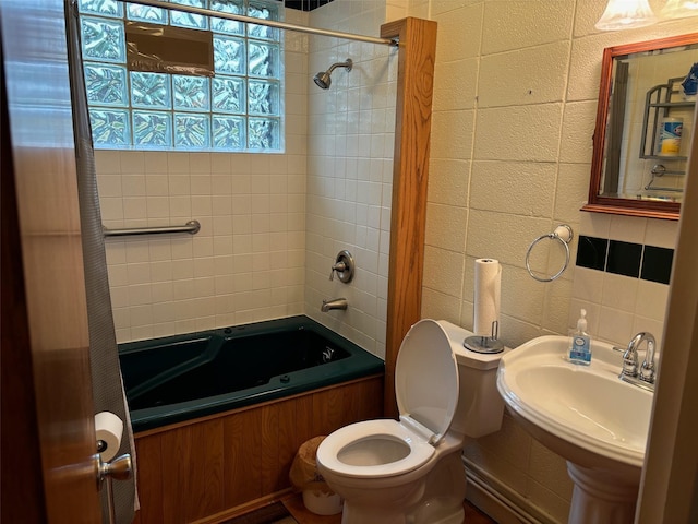 bathroom featuring toilet, tile walls, shower / bath combo with shower curtain, and a sink