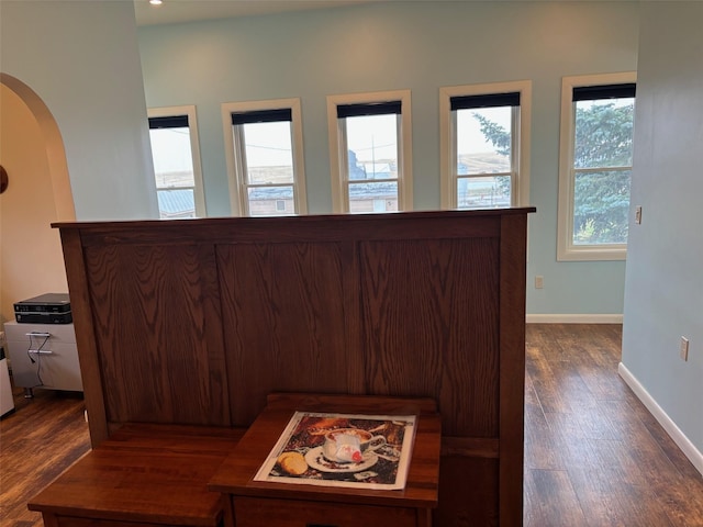 interior space featuring arched walkways, dark wood finished floors, and baseboards