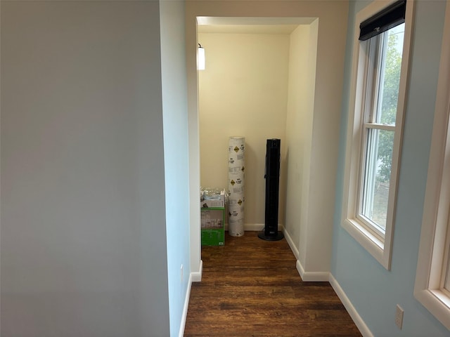 hallway featuring dark wood-type flooring and baseboards