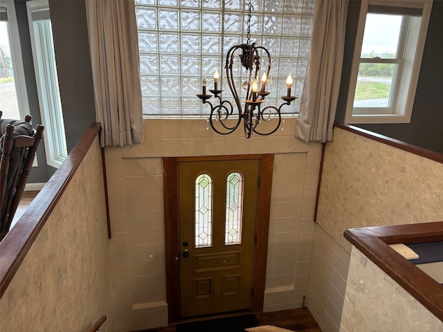 foyer featuring tile walls and a chandelier