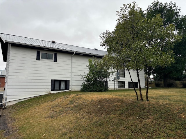 rear view of house with metal roof and a yard