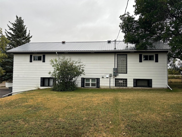 rear view of house featuring a yard and metal roof