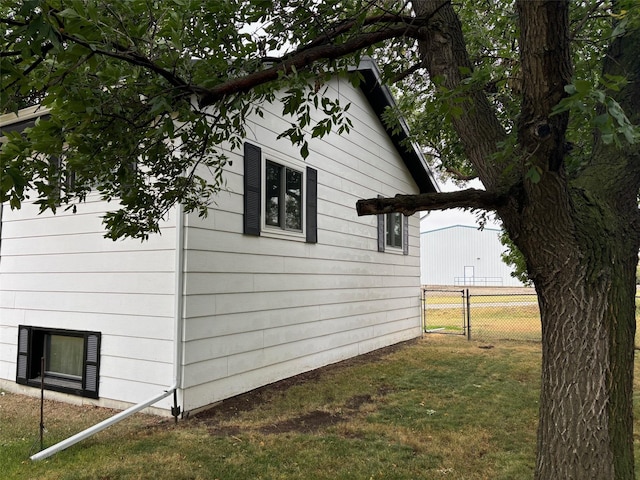 view of home's exterior featuring a lawn, fence, and a gate