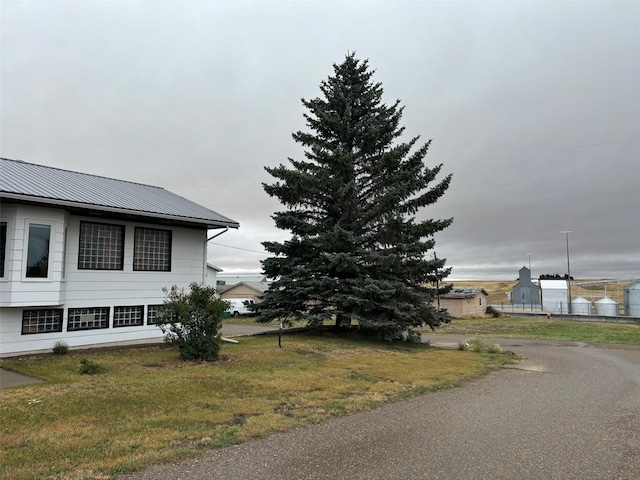 view of property exterior featuring metal roof and a lawn