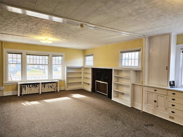 unfurnished living room with dark colored carpet and radiator