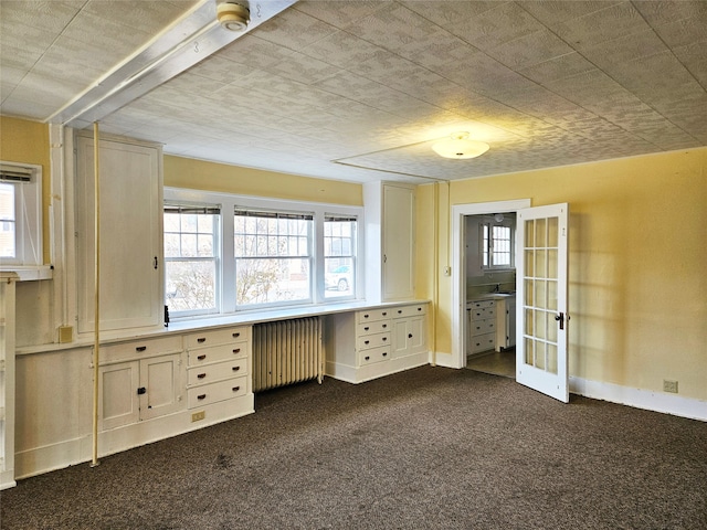 interior space featuring radiator heating unit, built in desk, and dark colored carpet