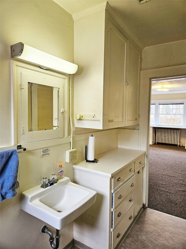 bathroom with ornamental molding, sink, and radiator