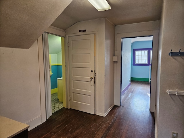 hallway featuring a textured ceiling, dark hardwood / wood-style floors, and vaulted ceiling