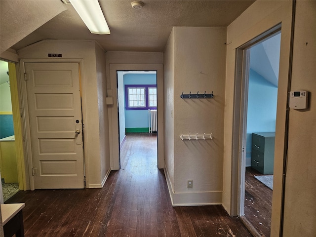 hallway featuring a textured ceiling, radiator, and dark wood-type flooring