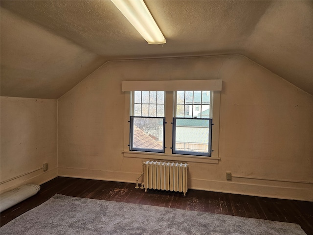 bonus room with dark wood-type flooring, a textured ceiling, radiator, and vaulted ceiling