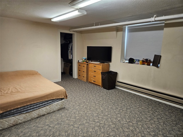 carpeted bedroom featuring a textured ceiling, a spacious closet, a closet, and a baseboard heating unit