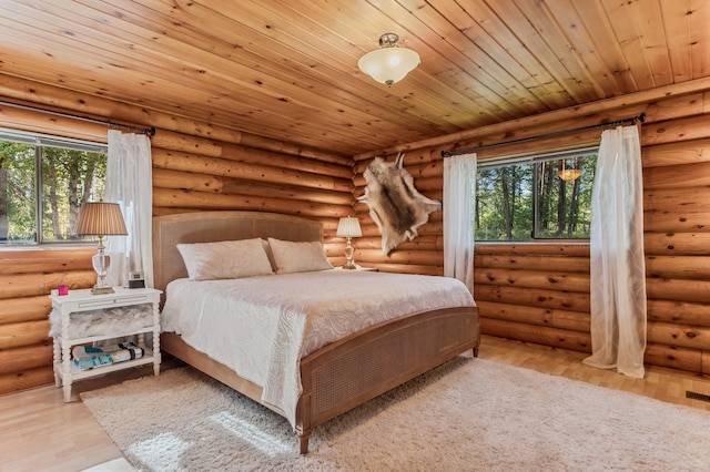 bedroom with light wood-type flooring, multiple windows, and rustic walls