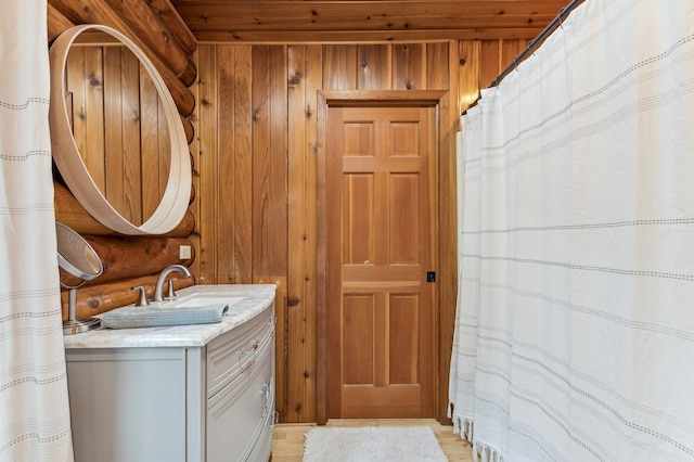 bathroom with vanity, hardwood / wood-style floors, and wooden walls