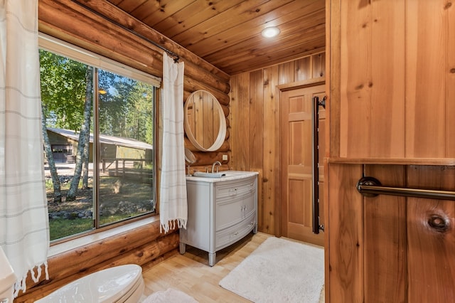 bathroom with toilet, hardwood / wood-style floors, vanity, wood walls, and wood ceiling