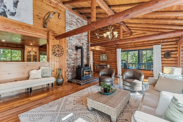 living room featuring high vaulted ceiling, a wealth of natural light, a wood stove, and wood-type flooring