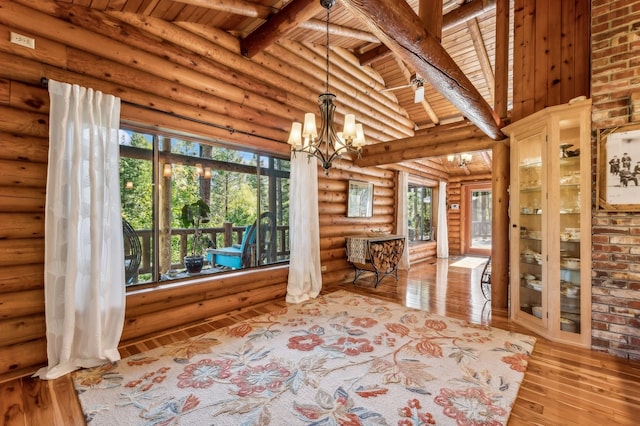 interior space featuring a wealth of natural light, a chandelier, and lofted ceiling with beams