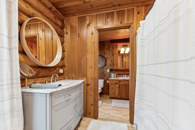 bathroom featuring vanity, toilet, and wood walls