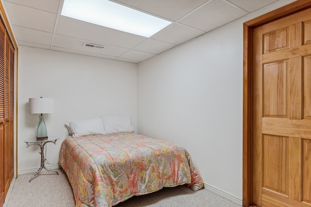 carpeted bedroom with a closet and a drop ceiling