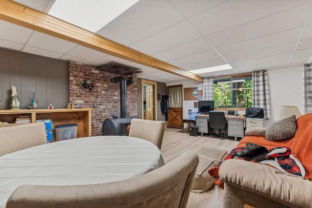 interior space featuring wood-type flooring, a wood stove, and a drop ceiling