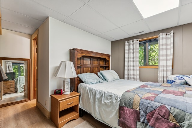 bedroom featuring multiple windows, hardwood / wood-style flooring, and a drop ceiling