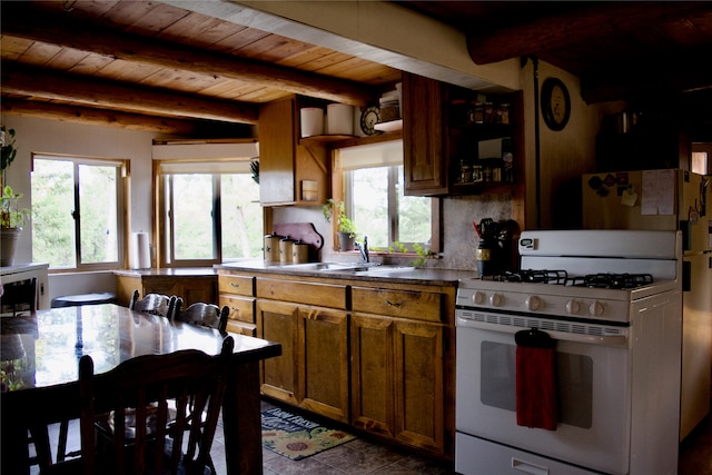 kitchen with white range with gas cooktop, beamed ceiling, and a healthy amount of sunlight