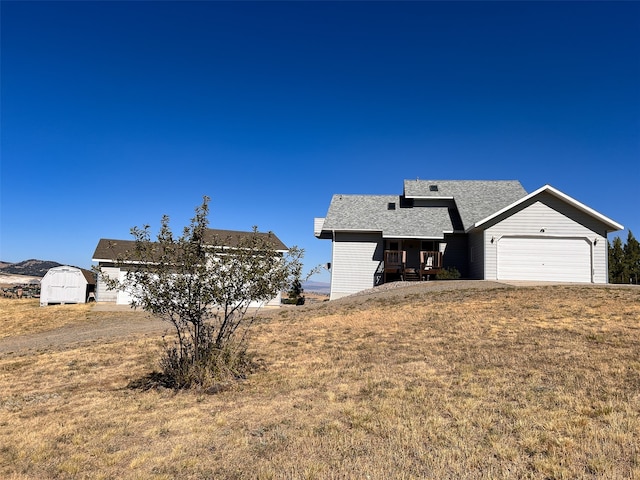 view of front facade featuring a storage shed, a garage, and a front lawn