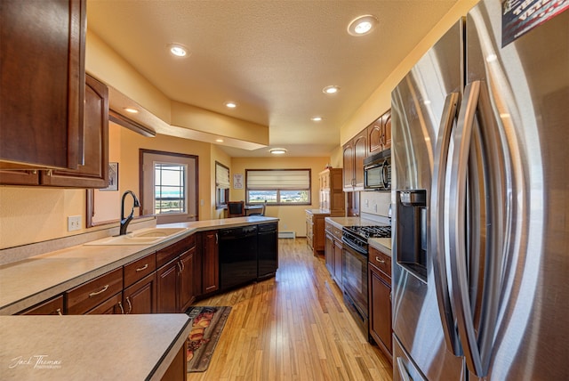 kitchen featuring light hardwood / wood-style flooring, a baseboard heating unit, sink, black appliances, and a textured ceiling