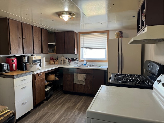 kitchen with dark wood-type flooring, white refrigerator, gas stove, dark brown cabinetry, and washer / clothes dryer