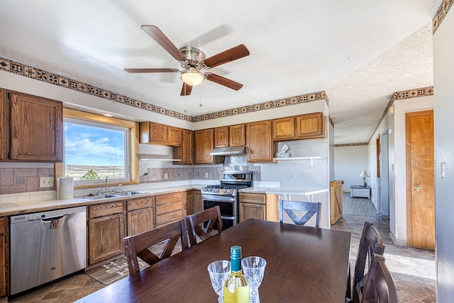 kitchen with sink, appliances with stainless steel finishes, ceiling fan, a textured ceiling, and backsplash