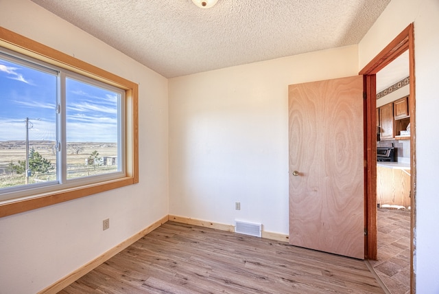 unfurnished room with a textured ceiling and light hardwood / wood-style flooring