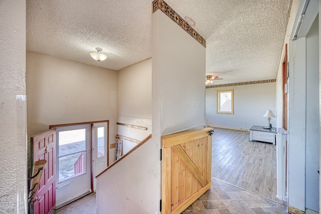 entrance foyer with a barn door, hardwood / wood-style floors, a textured ceiling, and ceiling fan