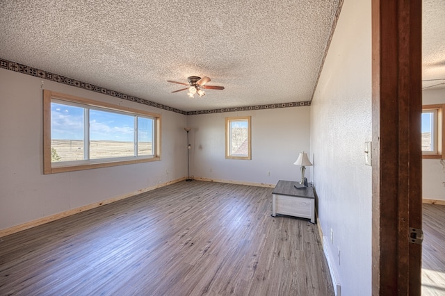 unfurnished room featuring a textured ceiling, light hardwood / wood-style floors, a wealth of natural light, and ceiling fan