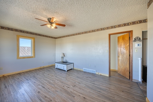 spare room with a textured ceiling, hardwood / wood-style flooring, and ceiling fan