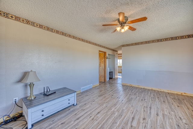 unfurnished room with ceiling fan, a textured ceiling, and light wood-type flooring