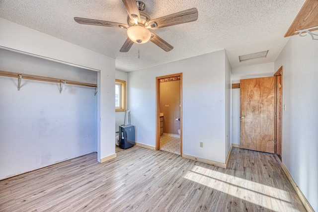 unfurnished bedroom featuring a closet, light wood-type flooring, a textured ceiling, ceiling fan, and ensuite bathroom