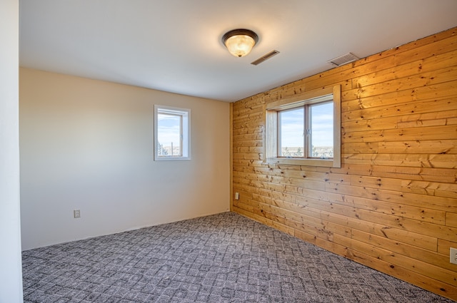 spare room featuring a healthy amount of sunlight, carpet flooring, and wooden walls