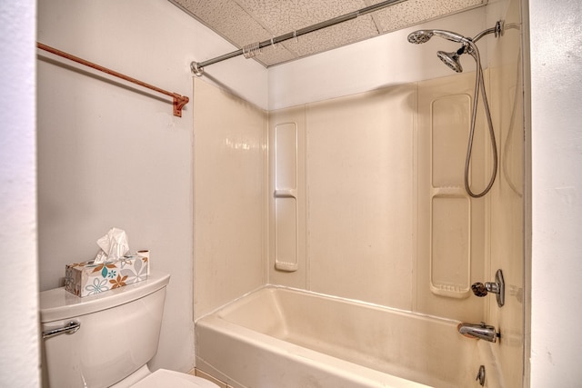 bathroom featuring a drop ceiling, washtub / shower combination, and toilet