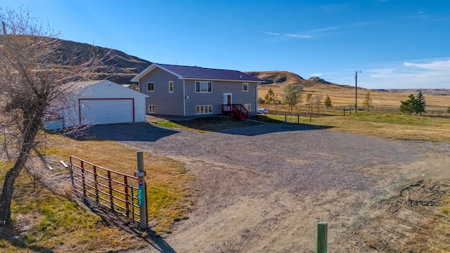 view of front of house featuring a garage, a rural view, a mountain view, and an outdoor structure