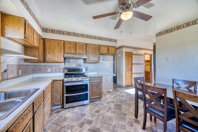 kitchen with sink, ceiling fan, range with two ovens, and decorative backsplash