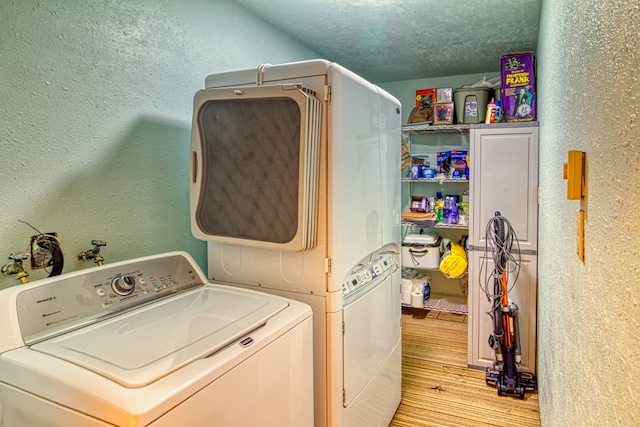 laundry area featuring light wood-type flooring, washer and clothes dryer, and a textured ceiling