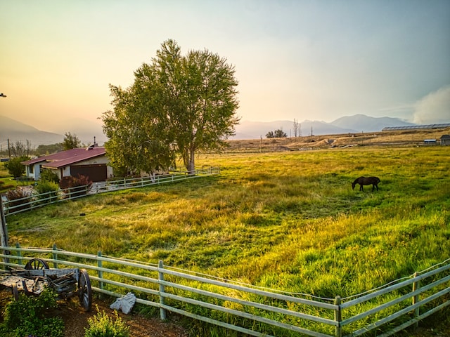 yard at dusk featuring a mountain view and a rural view