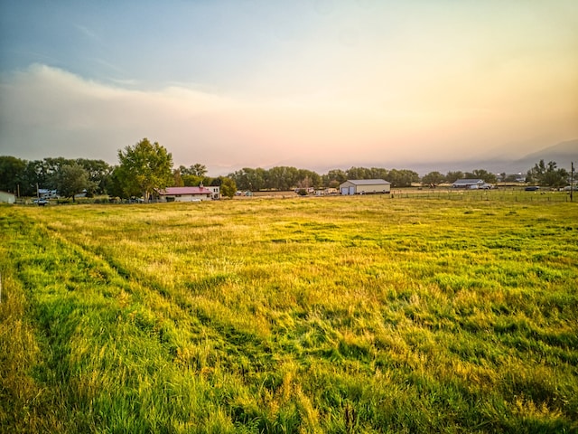 yard at dusk featuring a rural view